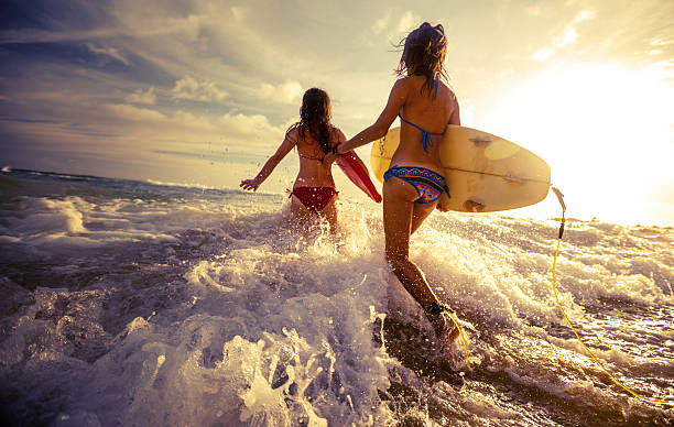 Two ladies running into the sea with surf boards